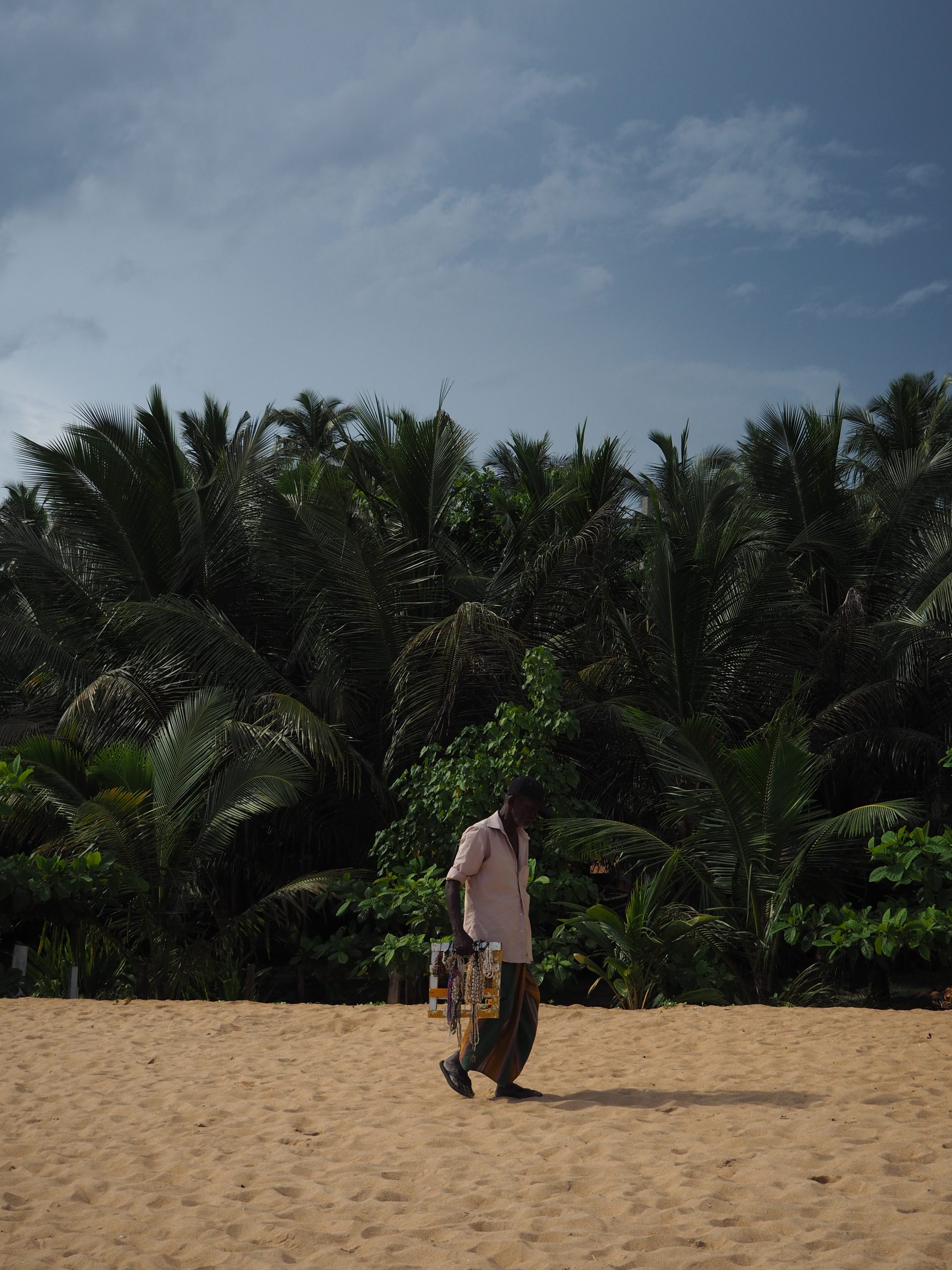 Sri Lankan man walking along the beach selling jewelry